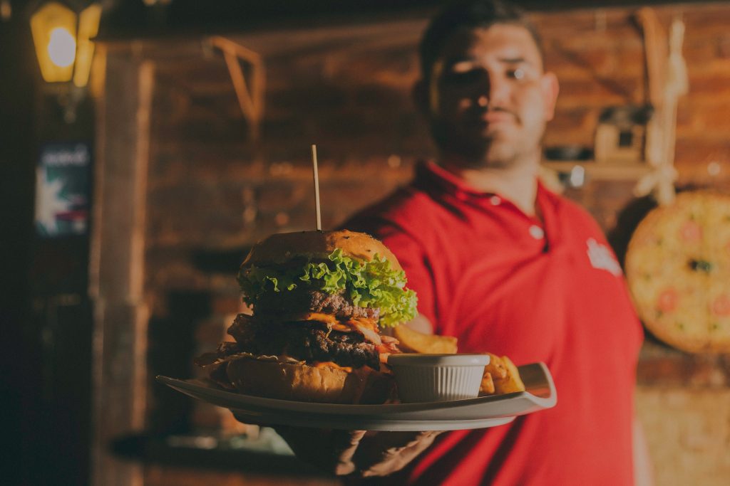 Man holding out a huge burger with cheese