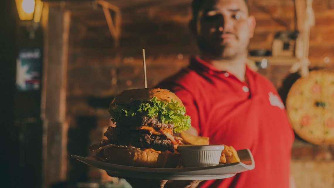 Man holding out a huge burger with cheese