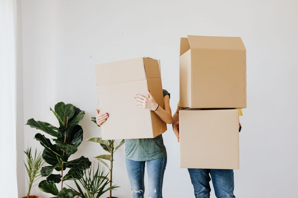2 people holding boxes ahead of a house move