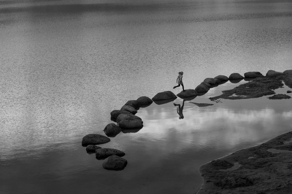 Woman running over stepping stone in the ocean