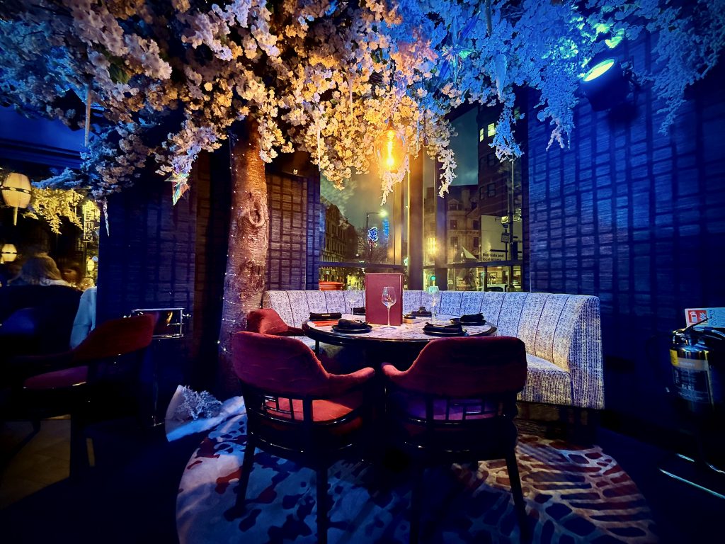 A stunning dining setup at Tattu Leeds featuring elegant cherry blossom decor, luxurious seating, and ambient lighting, showcasing the restaurant's grand atmosphere.