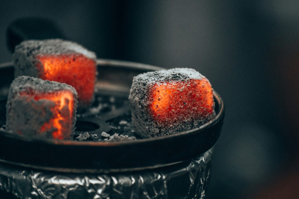 Close-up of glowing shisha charcoal cubes on a foil-covered hookah bowl, perfect for enjoying a premium Shisha on Wheels Dubai experience.