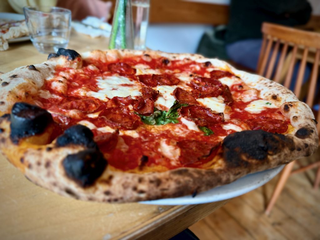 A freshly baked wood-fired pepperoni pizza at Anello Pizza in Slaithwaite, featuring a perfectly blistered crust, rich tomato sauce, gooey mozzarella, and crisp slices of pepperoni, served on a rustic wooden table.