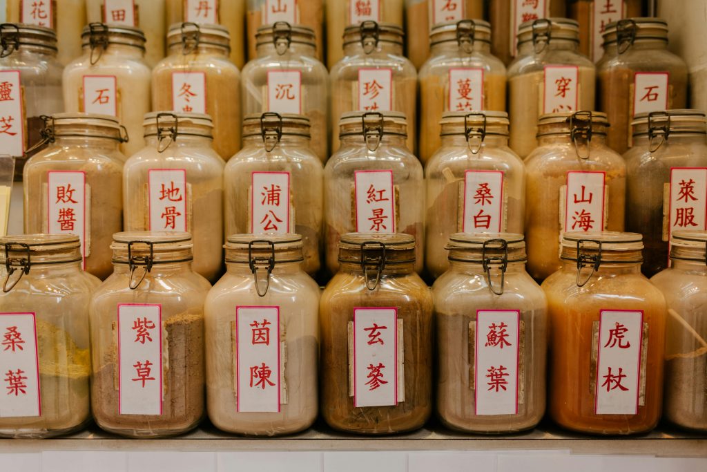 Rows of glass jars filled with various herbal powders, labeled with Chinese characters, neatly displayed in a traditional herbal medicine shop.