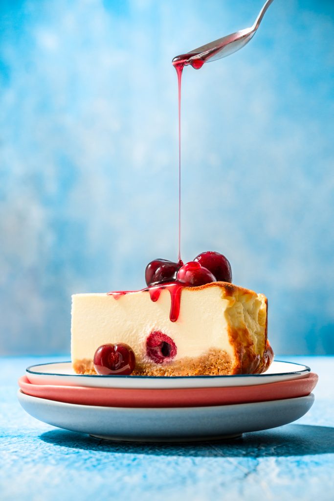 Picota Cherry Basque Cheesecake with a caramelised top, served with glossy cherry syrup and whole Picota cherries on a rustic plate