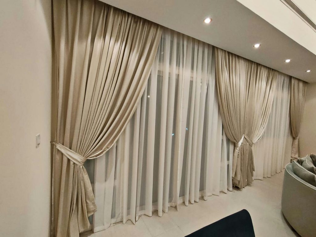 Elegant floor-to-ceiling beige curtains with sheer white lining in a modern interior, designed for both acoustic control and aesthetic appeal.