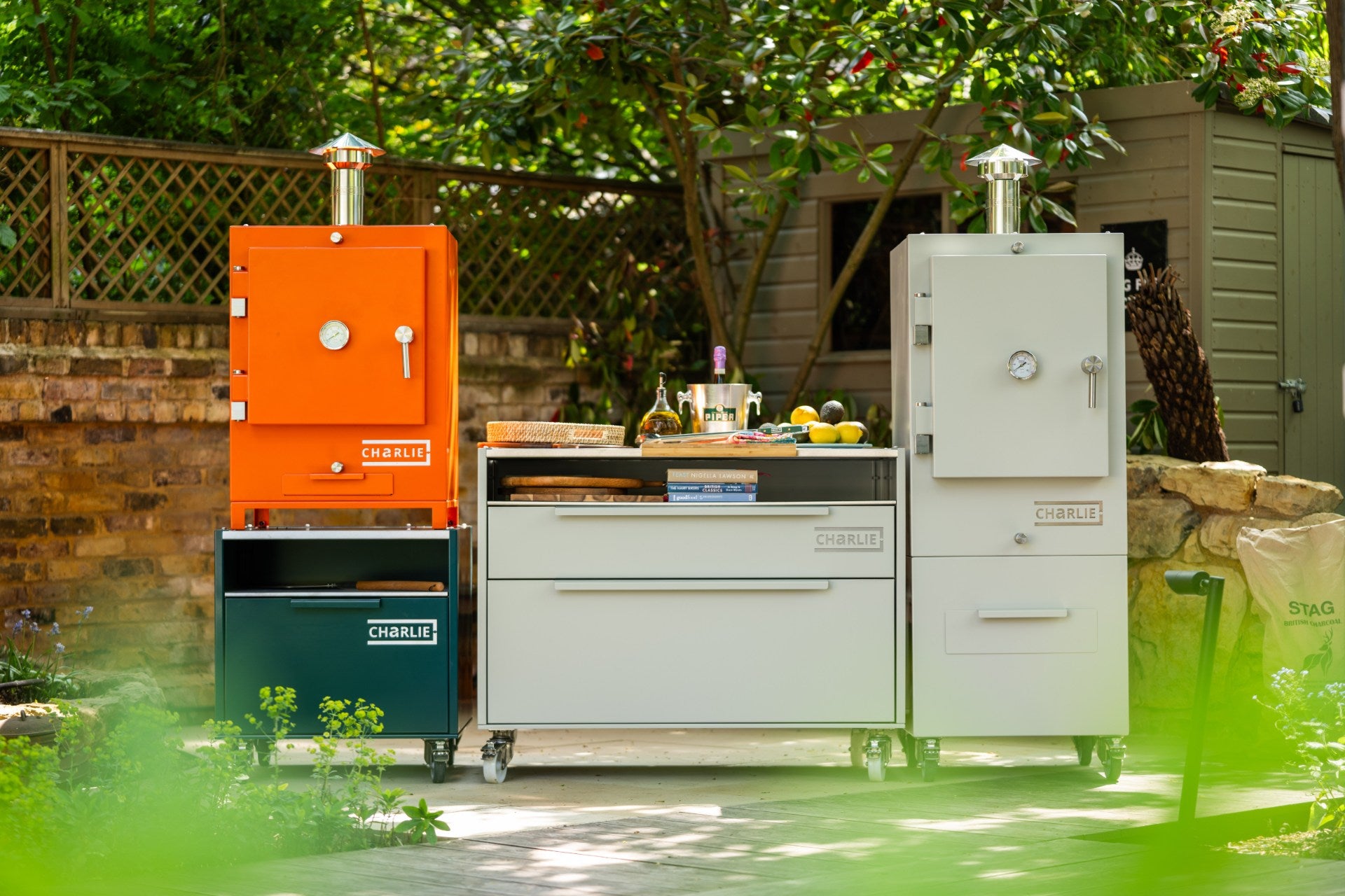 Charlie Charcoal Oven in a modern outdoor kitchen, premium black powder-coated finish with chimney, showcasing durable design for grilling, roasting, baking and smoking.