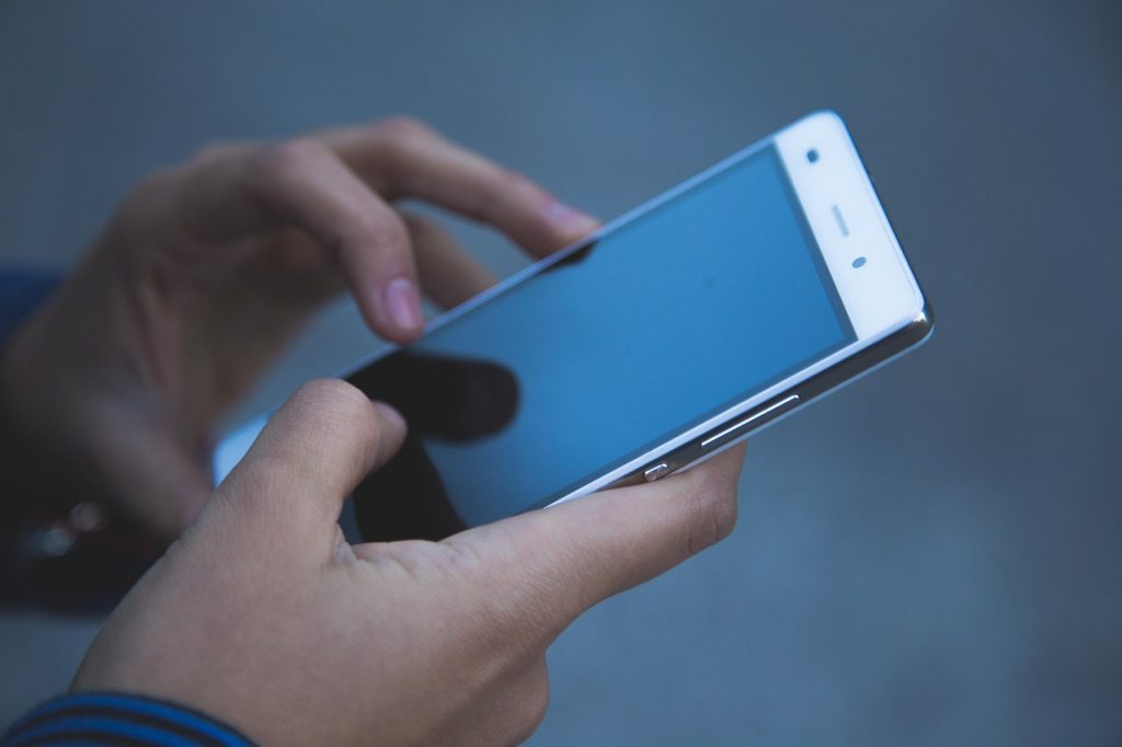 Close-up of a person using a smartphone, focusing on their hands holding the device and interacting with the touchscreen.