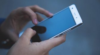 Close-up of a person using a smartphone, focusing on their hands holding the device and interacting with the touchscreen.