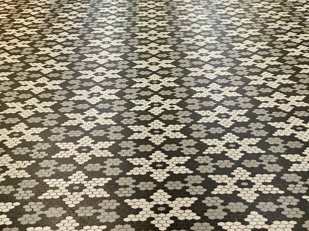 Patterned black, grey, and white hexagonal tile flooring arranged in a star-shaped geometric design, creating a stylish and modern surface suitable for contemporary interiors.