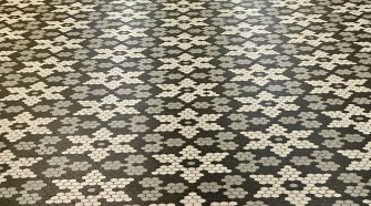 Patterned black, grey, and white hexagonal tile flooring arranged in a star-shaped geometric design, creating a stylish and modern surface suitable for contemporary interiors.
