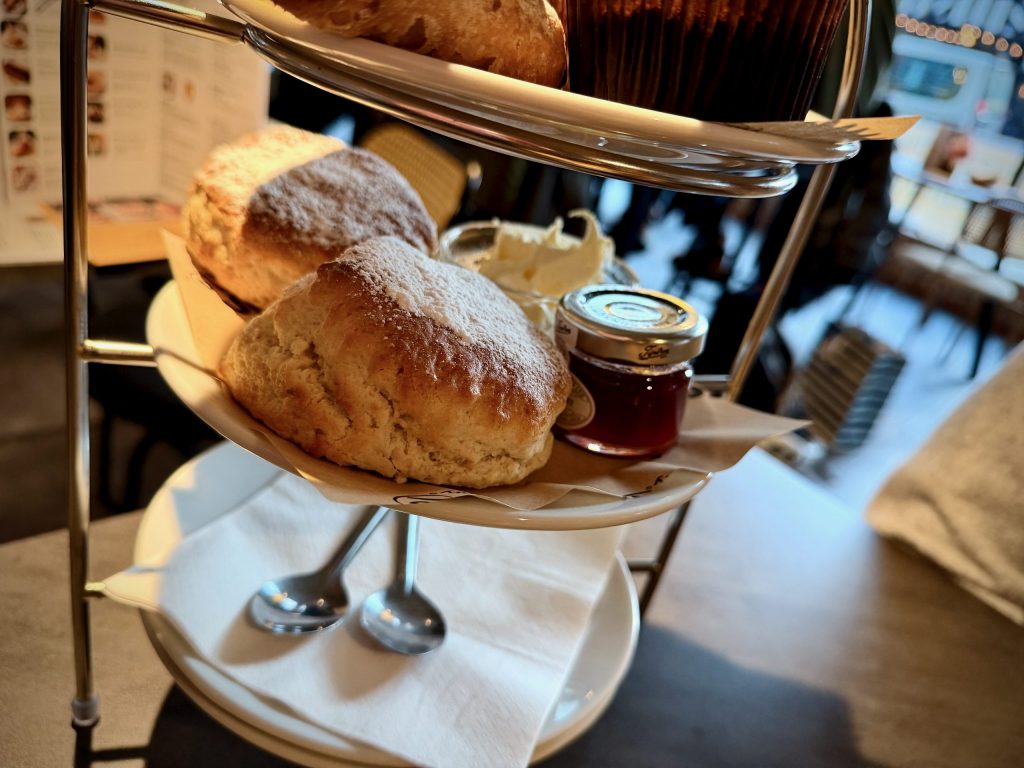 Close-up of large scones on an afternoon tea stand with a jar of jam and clotted cream at Nesso Leeds.