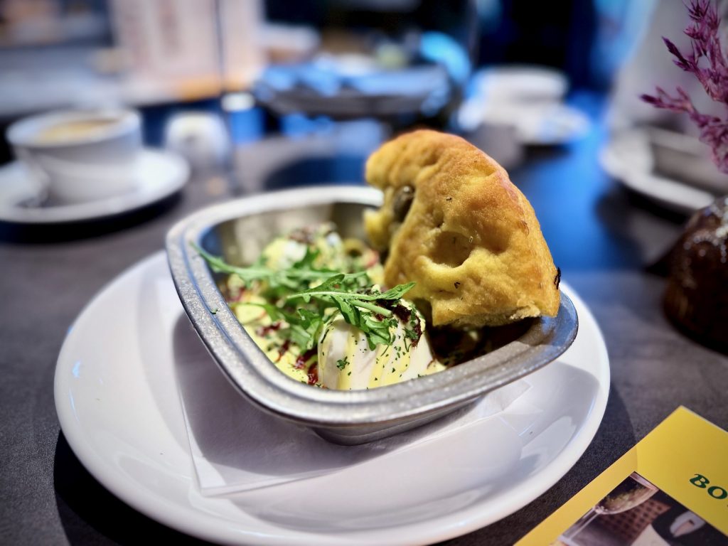 Savoury course served in a small tin dish with salad and bread, photographed on a table at Nesso in Leeds.