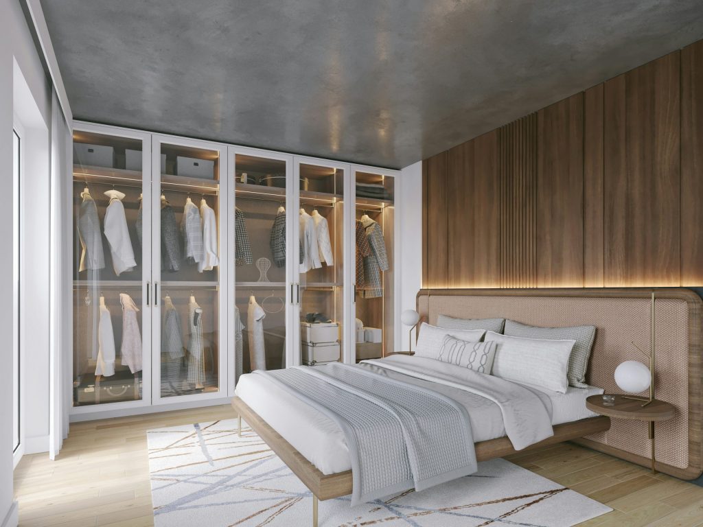 Built-in wardrobes over bed in a modern bedroom, featuring floor-to-ceiling glass-fronted storage, integrated lighting, and a neutral, minimalist design that maximises space and keeps the room uncluttered.
