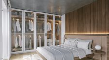 Built-in wardrobes over bed in a modern bedroom, featuring floor-to-ceiling glass-fronted storage, integrated lighting, and a neutral, minimalist design that maximises space and keeps the room uncluttered.
