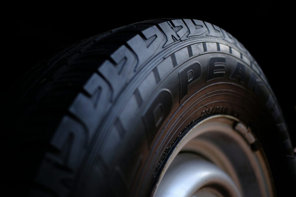 Close-up of a car tyre and alloy wheel, showing the tread and sidewall detail against a dark background.