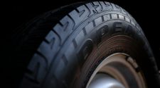 Close-up of a car tyre and alloy wheel, showing the tread and sidewall detail against a dark background.