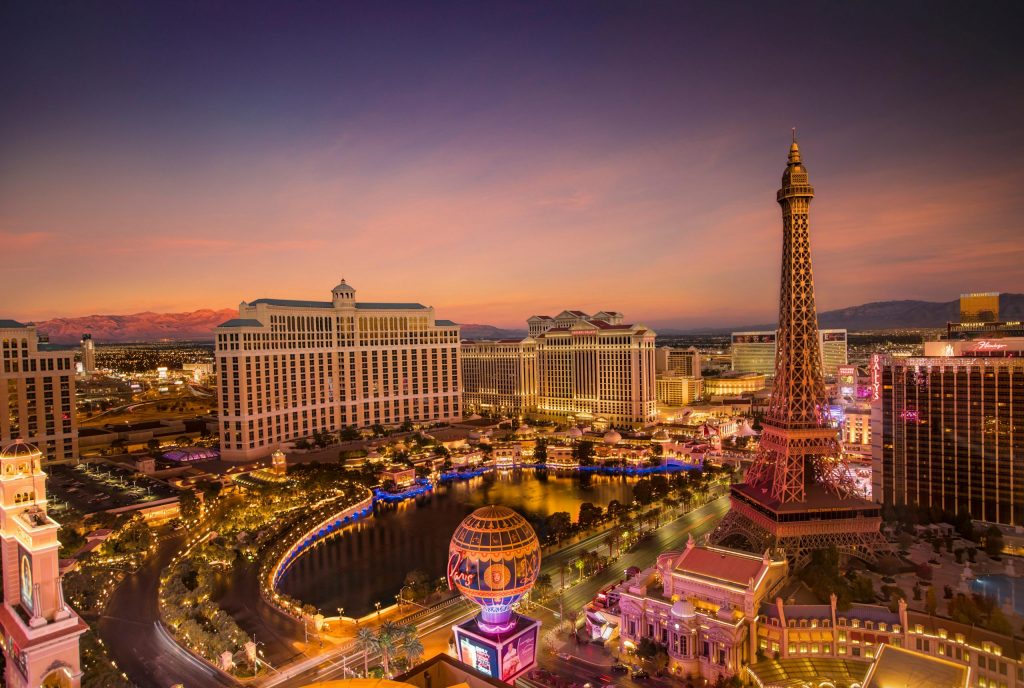 Las Vegas Strip at sunset featuring the Bellagio fountains and the Eiffel Tower replica glowing against the city skyline.