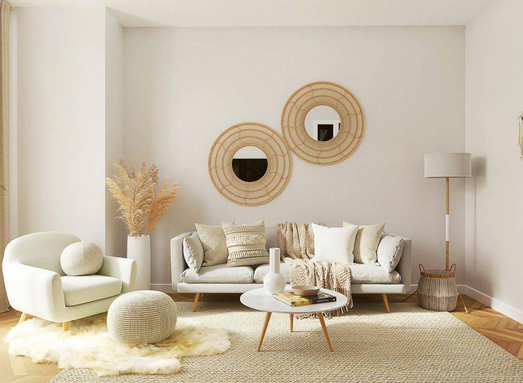 Light, neutral-toned living room with a beige sofa, textured cushions and throws, a matching armchair, woven wall mirrors, soft rug, wooden coffee table, and floor lamp, creating a calm and comfortable space.