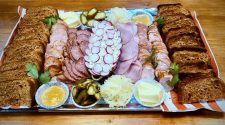 Traditional Polish rye bread served sliced with cold meats, pickles and mustard on a wooden table