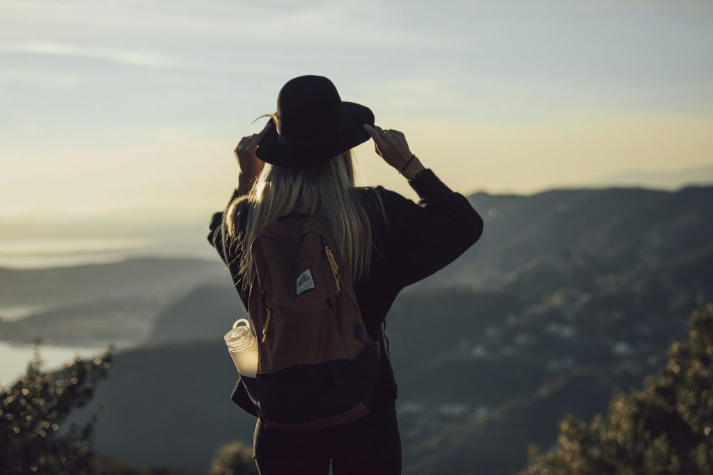 Solo traveller with backpack overlooking scenic mountains at sunset, capturing the freedom and independence of solo travel