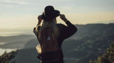 Solo traveller with backpack overlooking scenic mountains at sunset, capturing the freedom and independence of solo travel