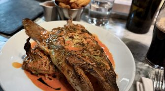 Fallow London smoked cod’s head served with sriracha sauce, plated at the chef’s counter with fries and kitchen action in the background