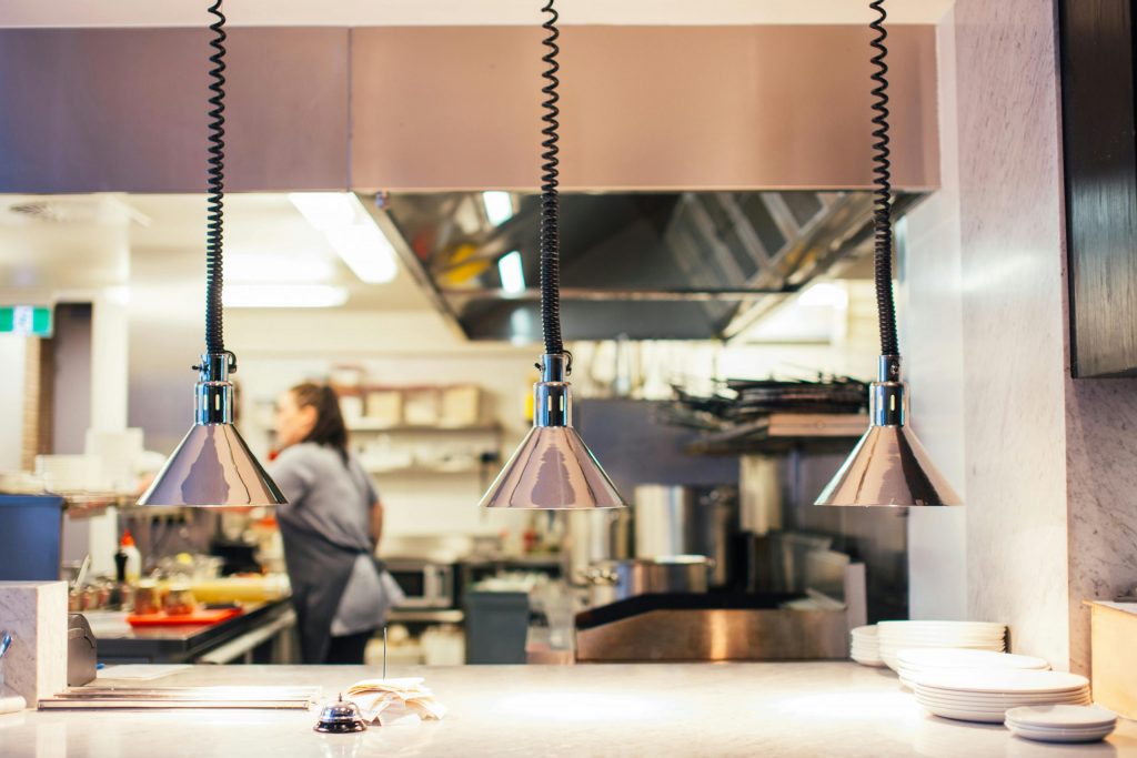 Modern commercial kitchen interior with serving pass and heat lamps, typical setup for a ghost kitchen operation