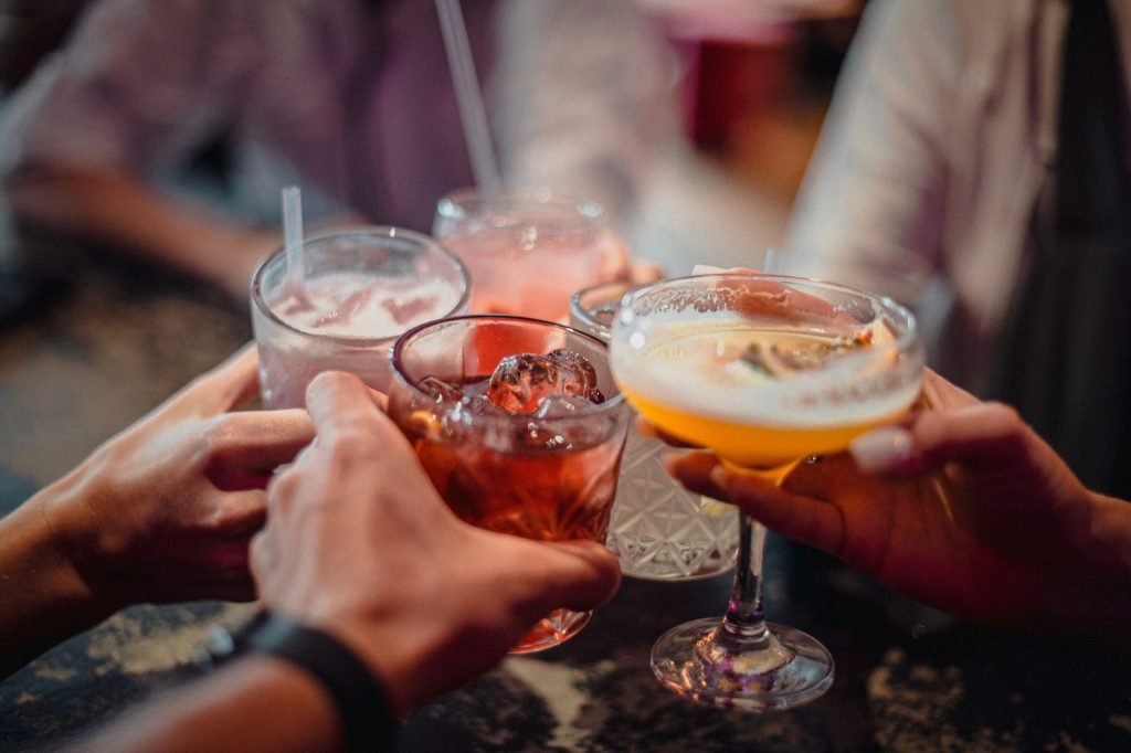 People raising cocktails and mixed drinks in a lively bar, capturing the festive atmosphere of a corporate Christmas party in Sheffield.