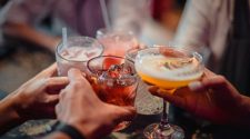 People raising cocktails and mixed drinks in a lively bar, capturing the festive atmosphere of a corporate Christmas party in Sheffield.