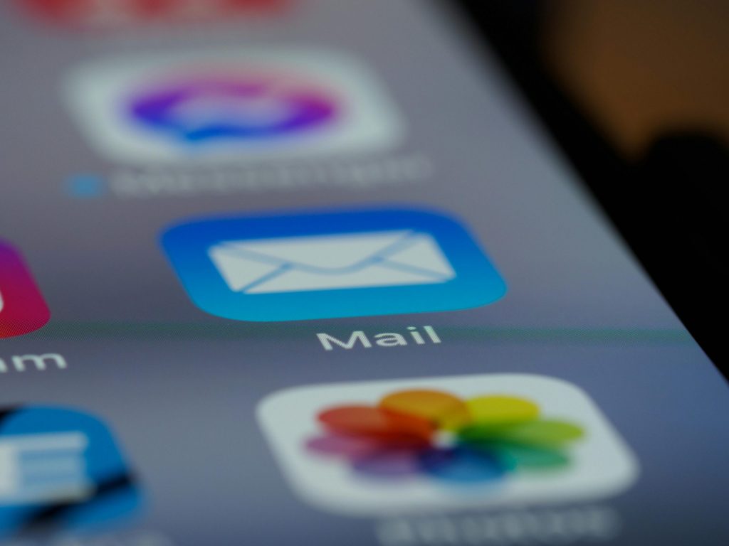 Close-up of a smartphone screen showing the Mail app icon, representing email organisation, inbox management and digital communication while travelling.