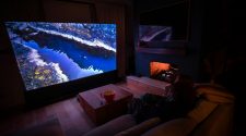 A cosy home theatre setup with a large screen, soft seating, fireplace, and dim ambient lighting for an immersive movie night experience.