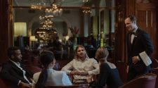 Business guests seated in a luxury private dining room while a waiter discusses the evening’s service, creating an executive dinner setting.