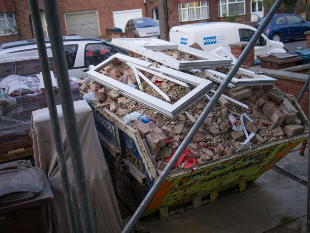 Construction skip filled with renovation rubble and window frames in Leeds