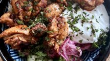 Chicken shawarma rice bowl served with fluffy rice, garlic yoghurt, pickled red onion, cucumber and chopped herbs in a patterned bowl.