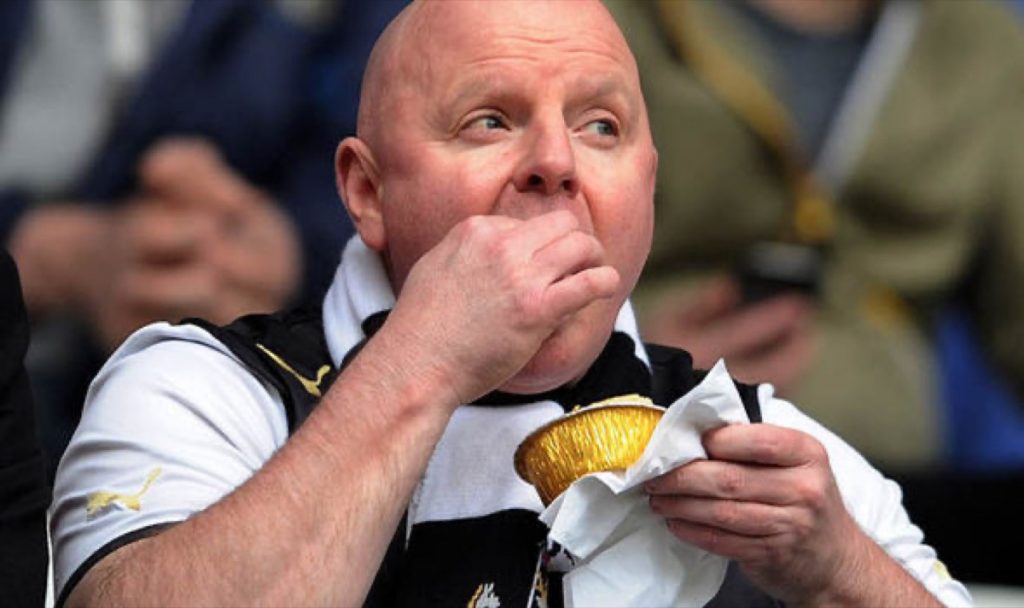Football supporter eating a matchday pie