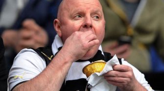Football supporter eating a matchday pie