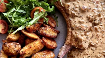 Steakhouse-style peppercorn pork chop with crispy garlic potatoes and rocket salad