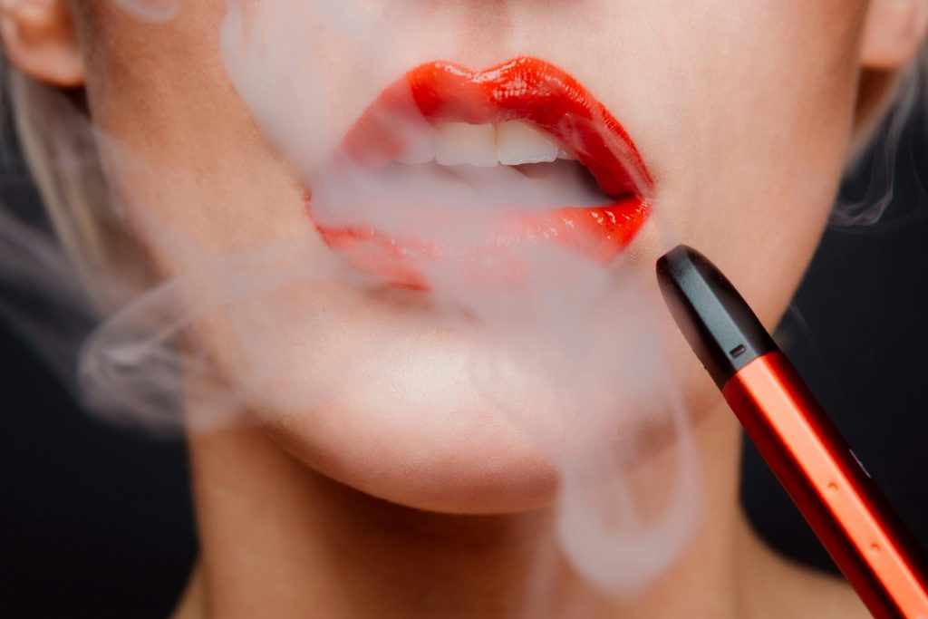 Woman with red lipstick with a vape