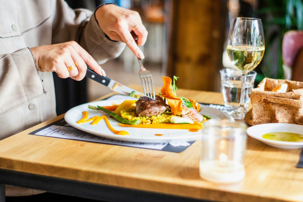 Restaurant reviewer eating a plated meal with wine