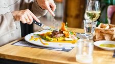 Restaurant reviewer eating a plated meal with wine