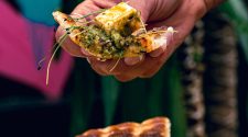 Flatbread topped with green sauce and cheese held above poached eggs and carrot ribbons at House of Koko Leeds
