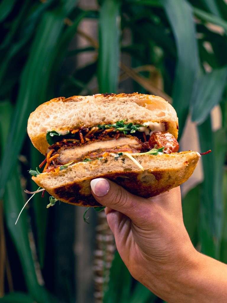 Toasted sandwich cut in half to show a breaded filling, tomato, greens and sauce at House of Koko Leeds