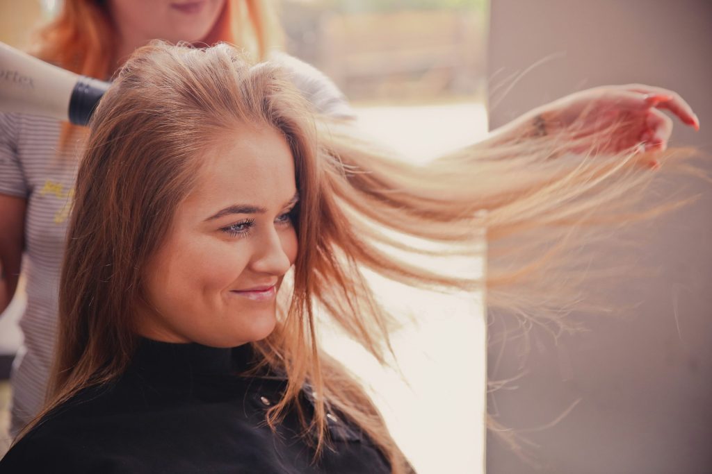 Woman having her hair styled for a blonde hair extensions transformation