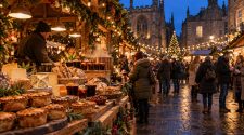 Yorkshire Christmas market food stall with artisan pies, cheese, bread and festive drinks at dusk