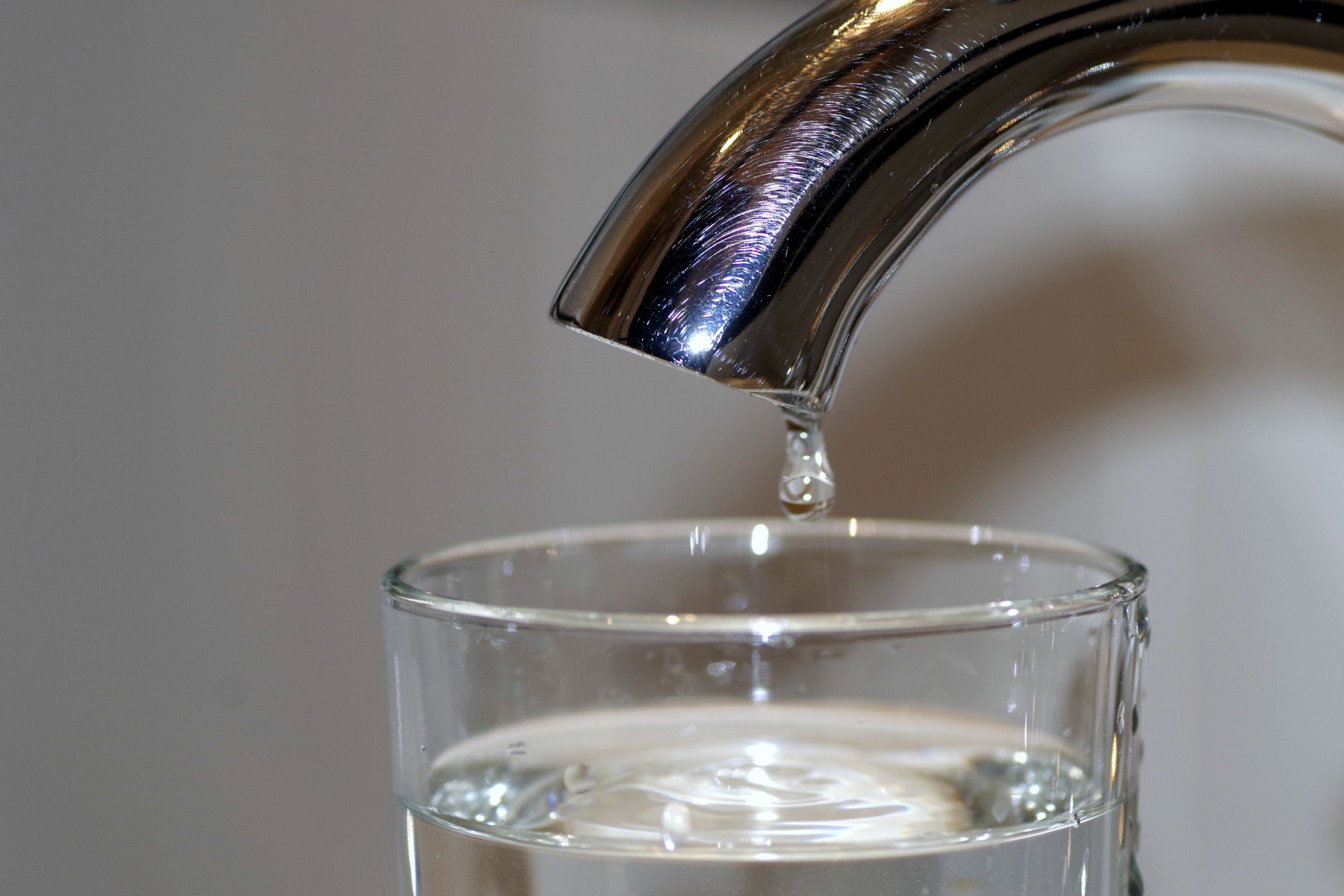 Filtered tap water dripping into a clear drinking glass