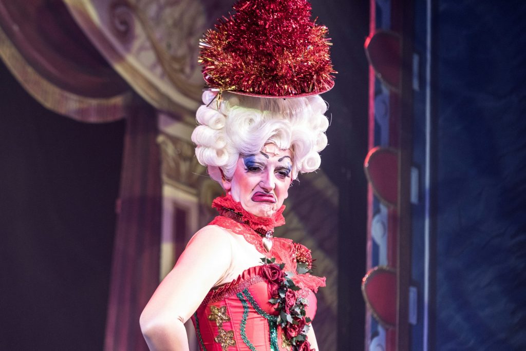 Drag performer in a red costume on stage during a cabaret show