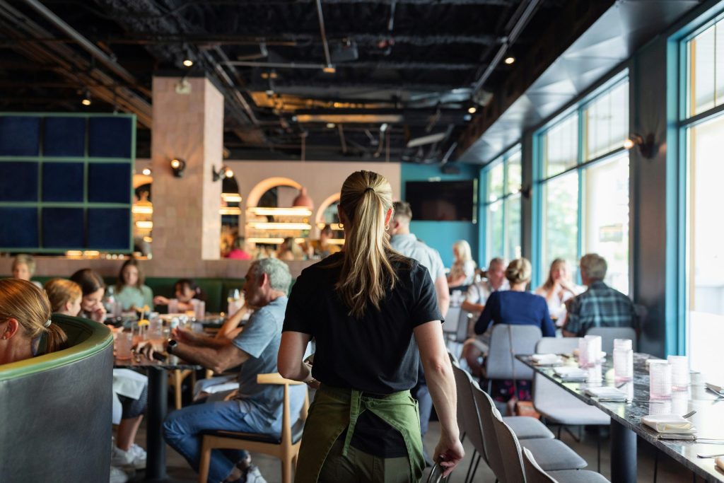 Restaurant server carrying chairs through a busy dining room