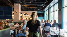 Restaurant server carrying chairs through a busy dining room